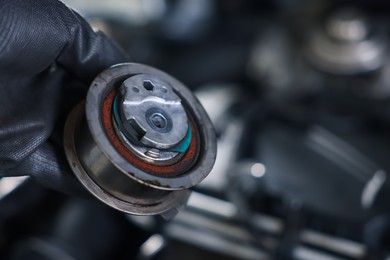 Photo of Auto part. Professional mechanic with idler-wheel near open hood of car indoors, closeup. Space for text