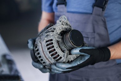 Photo of Auto part. Professional mechanic with alternator near indoors, closeup. Space for text