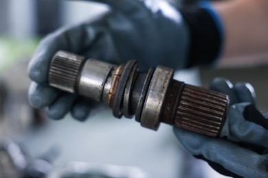 Photo of Auto part. Professional mechanic with drive shaft indoors, closeup