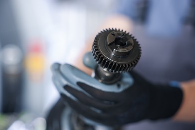 Photo of Auto part. Professional mechanic with camshaft indoors, selective focus