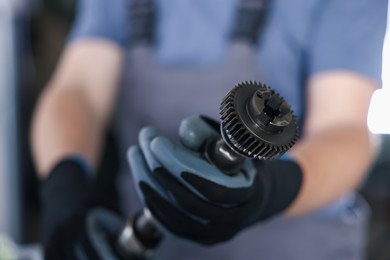 Photo of Auto part. Professional mechanic with camshaft indoors, selective focus