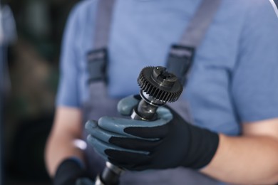 Photo of Auto part. Professional mechanic with camshaft indoors, closeup view
