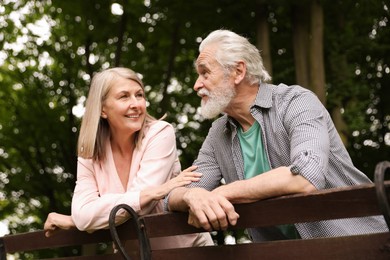 Photo of Lovely senior couple near wooden bench in park, low angle view