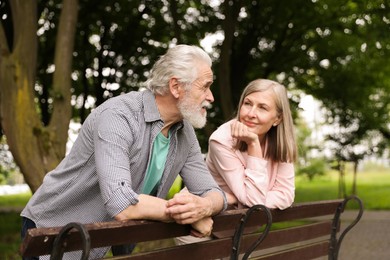 Photo of Lovely senior couple near wooden bench in park