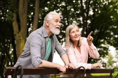 Photo of Lovely senior couple near wooden bench in park