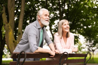 Photo of Lovely senior couple near wooden bench in park
