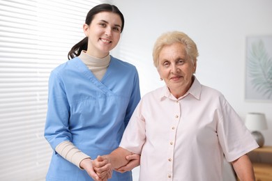 Photo of Nurse assisting senior woman indoors. Home health care service
