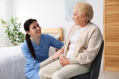 Photo of Nurse assisting senior woman indoors. Home health care service
