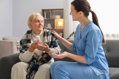 Photo of Nurse assisting senior woman indoors. Home health care service
