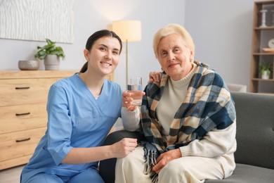 Photo of Nurse assisting senior woman indoors. Home health care service