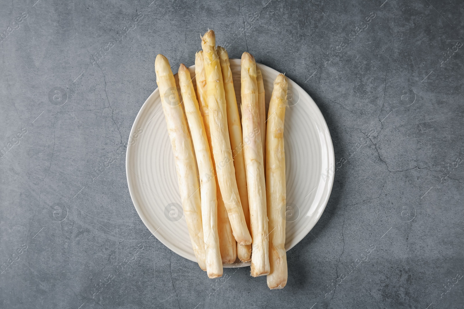 Raw white asparagus spears on grey textured table, top view Photo of Raw white asparagus spears on grey textured table, top view