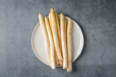 Photo of Raw white asparagus spears on grey textured table, top view