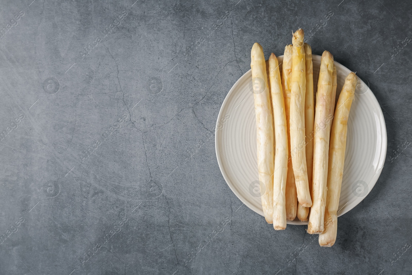 Raw white asparagus spears on grey textured table, top view. Space for text Photo of Raw white asparagus spears on grey textured table, top view. Space for text