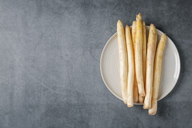 Photo of Raw white asparagus spears on grey textured table, top view. Space for text