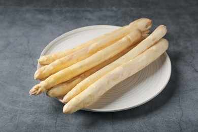 Photo of Raw white asparagus spears on grey textured table, closeup