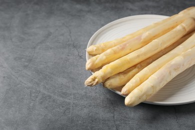 Photo of Raw white asparagus spears on grey textured table, closeup. Space for text