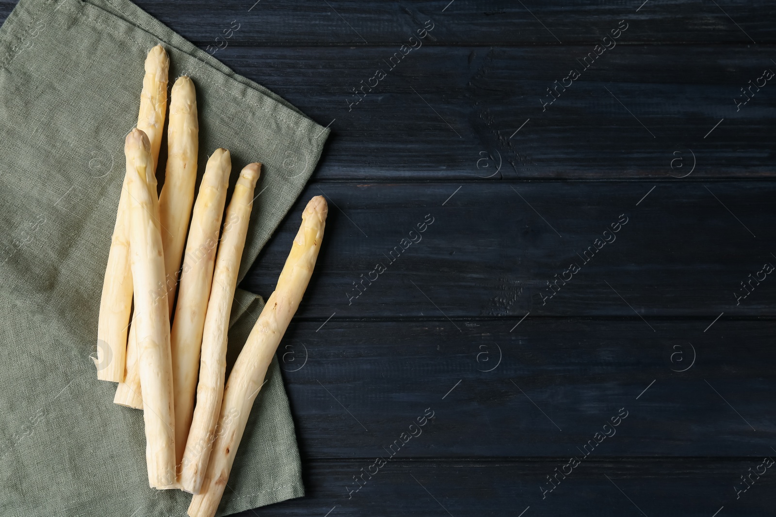Raw white asparagus spears on black wooden table, flat lay. Space for text Photo of Raw white asparagus spears on black wooden table, flat lay. Space for text