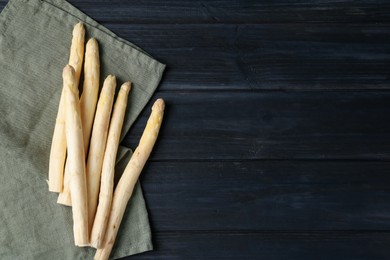 Photo of Raw white asparagus spears on black wooden table, flat lay. Space for text