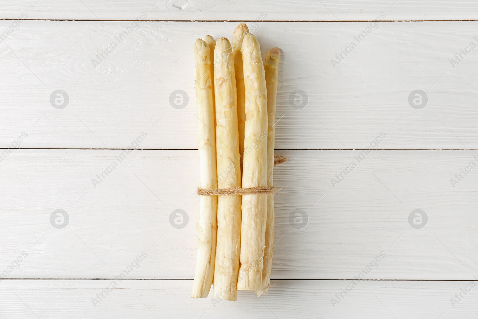 Bunch of raw asparagus spears on white wooden table, top view Photo of Bunch of raw asparagus spears on white wooden table, top view