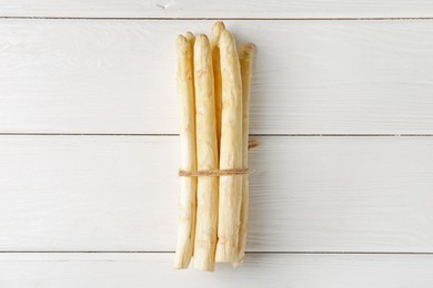 Photo of Bunch of raw asparagus spears on white wooden table, top view