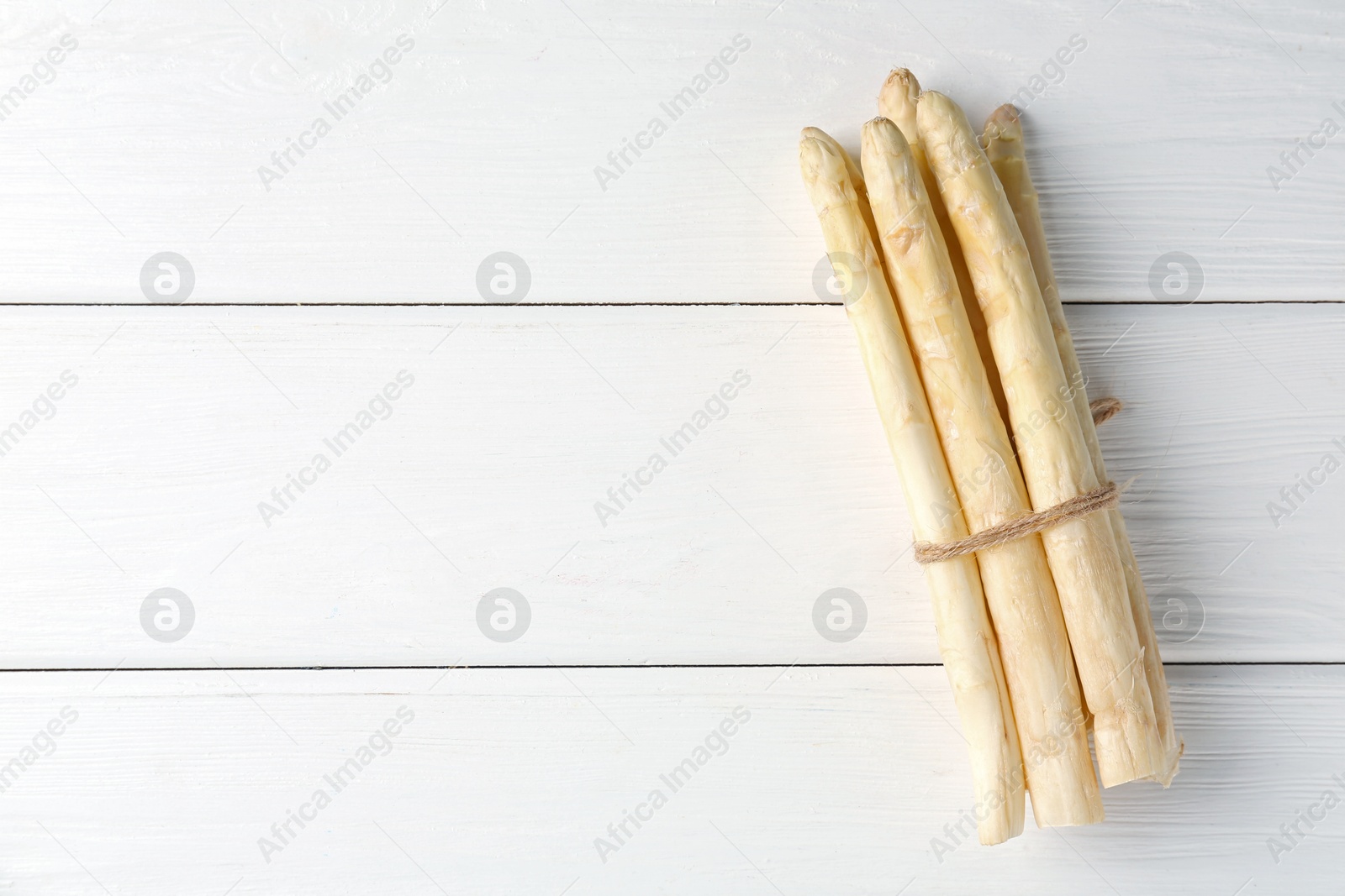 Bunch of raw asparagus spears on white wooden table, top view. Space for text Photo of Bunch of raw asparagus spears on white wooden table, top view. Space for text
