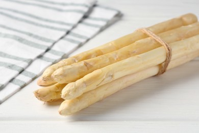 Photo of Bunch of raw asparagus spears on white wooden table, closeup