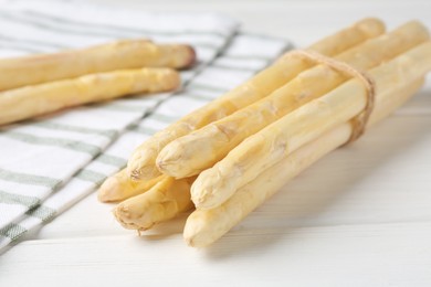 Photo of Bunch of raw asparagus spears on white wooden table, closeup