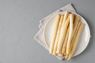 Photo of Raw white asparagus spears on grey textured table, top view. Space for text