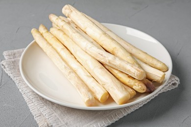 Photo of Raw white asparagus spears on grey textured table, closeup