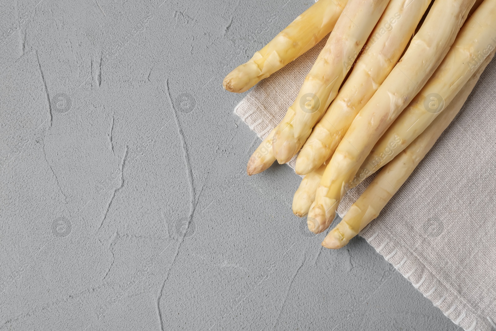 Raw white asparagus spears on grey textured table, top view. Space for text Photo of Raw white asparagus spears on grey textured table, top view. Space for text