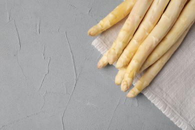 Photo of Raw white asparagus spears on grey textured table, top view. Space for text