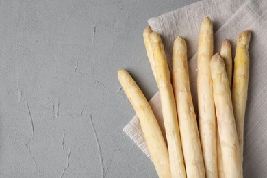 Photo of Raw white asparagus spears on grey textured table, top view. Space for text