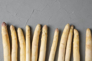 Photo of Raw white asparagus spears on grey textured table, flat lay. Space for text