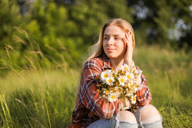 Photo of Beautiful woman with wildflowers enjoying summer day in meadow. Space for text