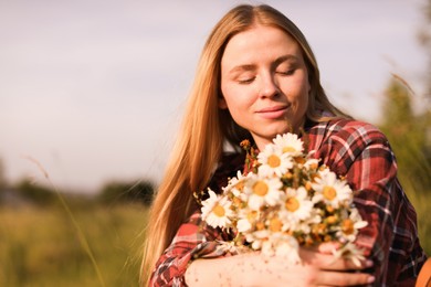 Photo of Beautiful woman with wildflowers enjoying summer day in meadow. Space for text