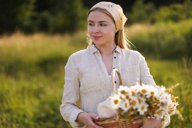 Photo of Happy woman with basket full of beautiful wildflowers outdoors