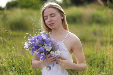 Photo of Beautiful woman with bouquet of wildflowers enjoying sunny day in meadow
