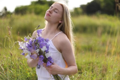 Photo of Beautiful woman with bouquet of wildflowers enjoying sunny day in meadow