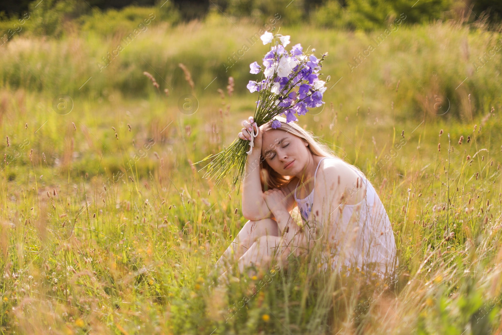 Photo of Beautiful woman with bouquet of wildflowers enjoying sunny day in meadow