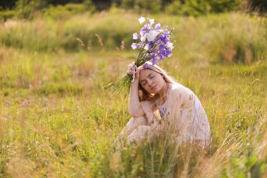 Photo of Beautiful woman with bouquet of wildflowers enjoying sunny day in meadow