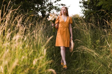 Photo of Beautiful woman with bouquet of wildflowers in meadow