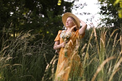 Photo of Beautiful woman with bouquet of wildflowers in meadow