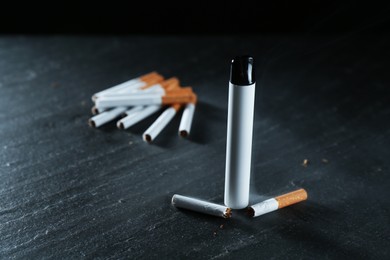Photo of Electronic smoking device and cigarettes on black table