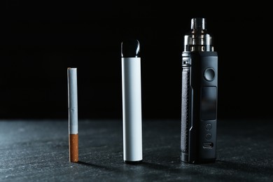 Photo of Electronic smoking devices and cigarettes on black table