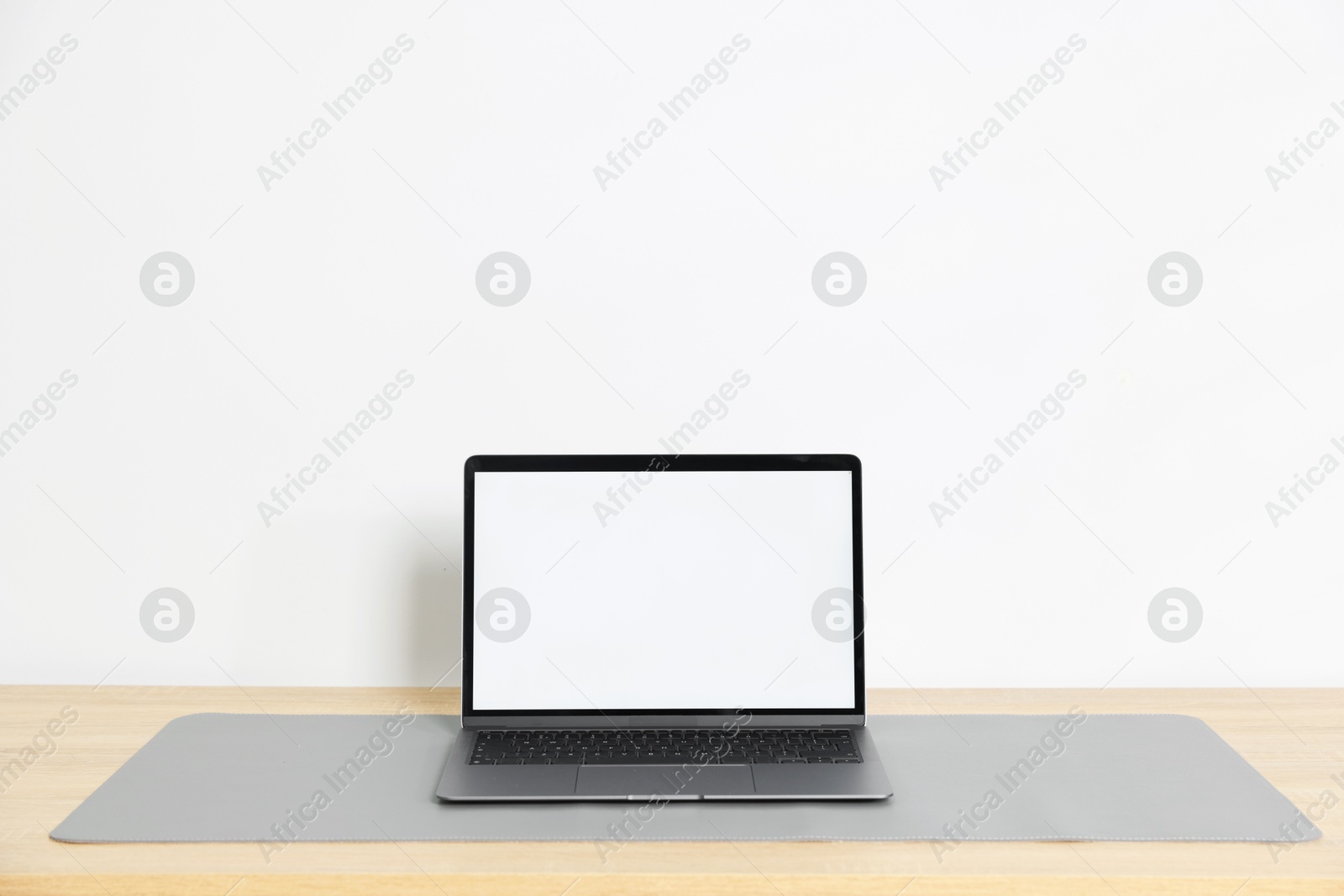 Photo of Stylish workplace with laptop and grey mousepad on wooden table indoors. Space for text