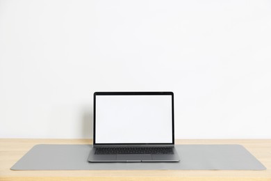 Photo of Stylish workplace with laptop and grey mousepad on wooden table indoors. Space for text