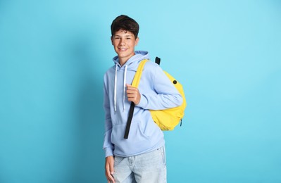 Photo of Teenage boy with backpack on light blue background
