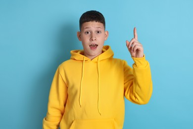 Photo of Teenage boy pointing at something on light blue background