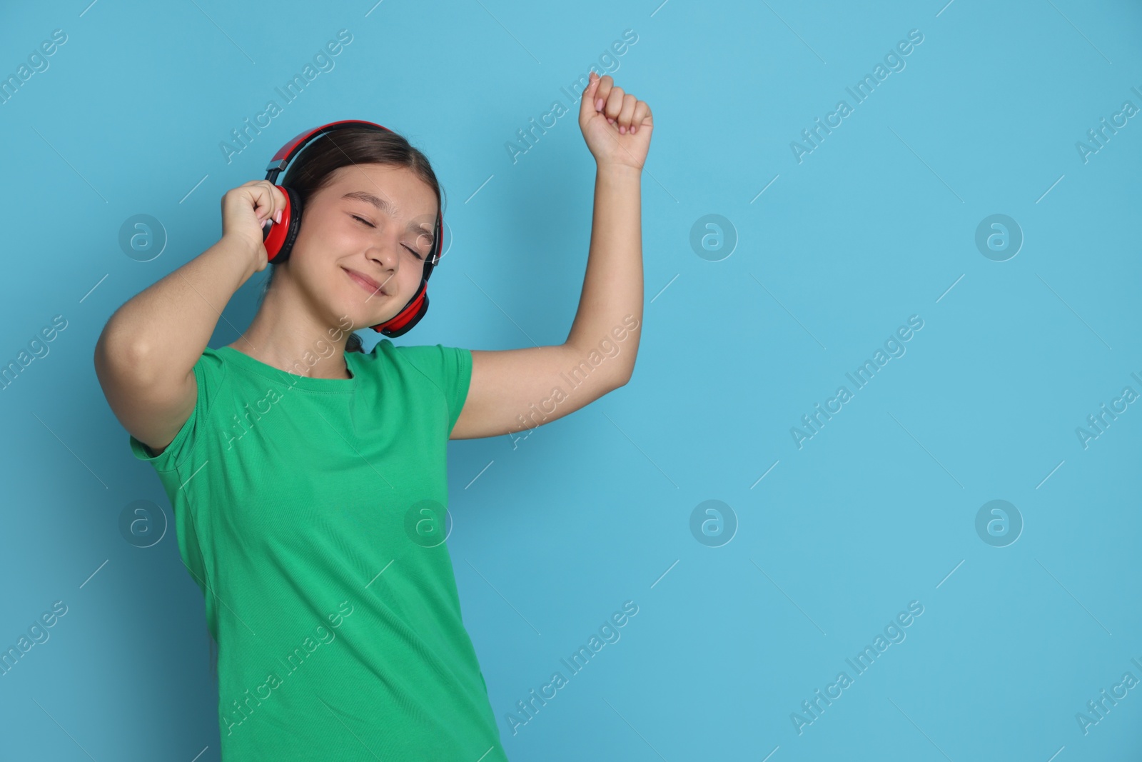 Teenage girl in headphones on light blue background, space for text Photo of Teenage girl in headphones on light blue background, space for text