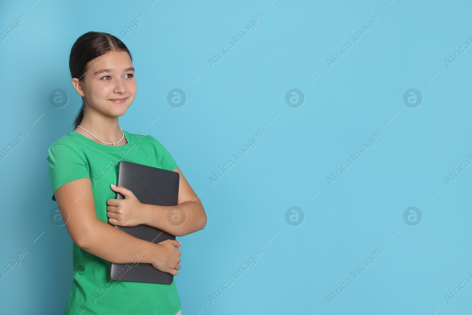 Teenage girl with laptop on light blue background, space for text Photo of Teenage girl with laptop on light blue background, space for text